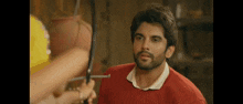 a man in a red sweater is standing next to a woman holding a hammer .