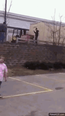 a girl in a pink shirt is walking down a street