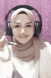 a woman wearing a hijab and headphones with a microphone .