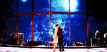 a man and a woman are standing in front of a large window looking at the moon .