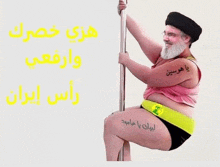 a man with a beard is sitting on a pole with arabic writing on his leg