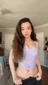 a woman in a purple tank top is standing in a room