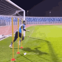 a man in a blue shirt is playing soccer on a field with a twitter account @imaanbaz