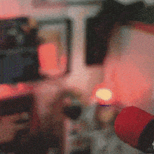 a person is holding a red microphone in front of a red light in a room .