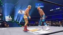 two men in a wrestling ring with the words all elite wrestling on the wall behind them