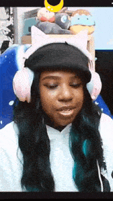a woman wearing headphones and a hat is sitting in front of a computer screen .