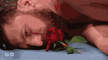 a man laying down with a rose in his mouth and a usa logo in the corner
