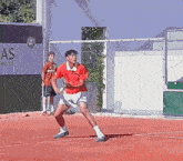 a man in a red shirt is playing tennis in front of a sign that says " as world "