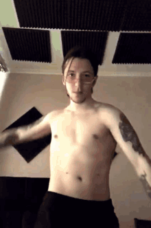 a shirtless man with glasses and a tattoo on his arm is dancing