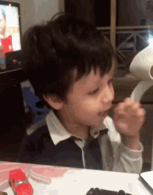 a young boy is sitting at a table with a red toy car