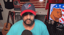 a man wearing a texans hat sits in front of a screen