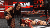 a female wrestler is kneeling next to another wrestler in a wrestling ring