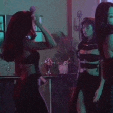 a woman in a black dress is dancing with another woman in a dark room