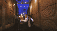 a man standing in an alleyway with a brick wall behind him