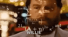 a man with a beard is standing in front of a computer screen with mathematical equations coming out of it .