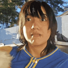 a woman wearing a blue and yellow shirt has a piercing in her lip