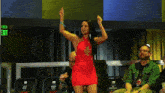 a woman in a red dress is standing in front of a green exit sign