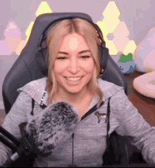 a woman wearing headphones and a pink shirt is sitting in a chair and smiling .