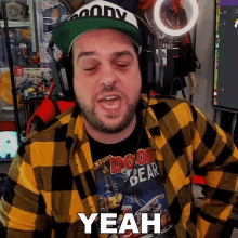 a man wearing a plaid shirt and a green hat says yeah