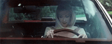 a woman is sitting in the driver 's seat of a car .