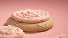 a cookie with pink frosting and sprinkles on a pink background