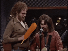 a man holding a corn dog stands next to a man playing a guitar
