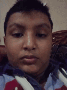 a close up of a young boy 's face with a red shirt on