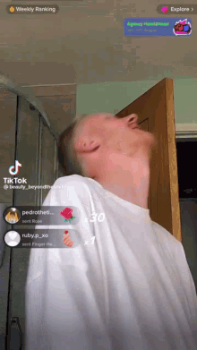 a man in a white shirt is standing in front of a door with a weekly ranking on the screen