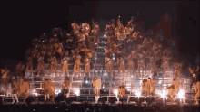 a woman in a yellow outfit is surrounded by a bunch of dancers