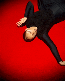 a woman is laying on her back on a red surface