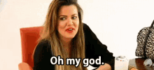 a woman is sitting at a table with a leopard print purse and says oh my god .