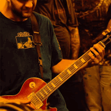 a man is playing a guitar with a shirt that says stille on it