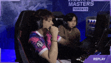 two men are playing a video game in front of a banner that says masters toronto