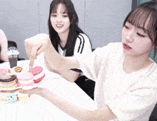 two girls sit at a table with a plate of macarons