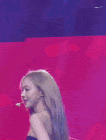 a woman in a black strapless dress is standing in front of a red background .