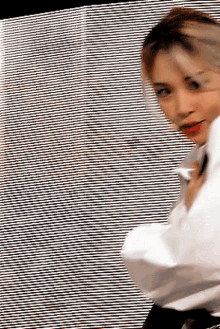 a woman in a white shirt is standing in front of a black and white striped wall