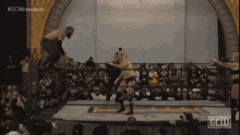 two men are wrestling in a ring with the letters gcw visible