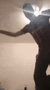 a man in a striped shirt is dancing in a dark room with a light shining on him .
