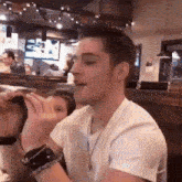 a man in a white shirt is sitting at a table with his mouth open