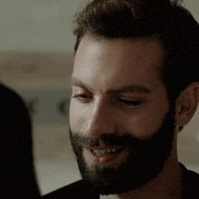 a man with a beard is smiling and looking at a woman