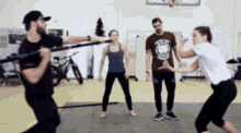 a group of people are practicing martial arts in a gym with a basketball hoop in the background