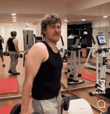 a man with a mustache is lifting dumbbells in front of a mirror in a gym