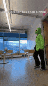 a person in a green suit and mask is walking in a room with the words " your location has been pinned " on the bottom