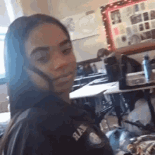 a girl is sitting at a table in a classroom with a backpack on .