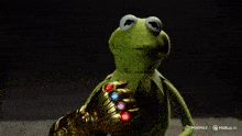 kermit the frog is holding a infinity gauntlet in his right hand
