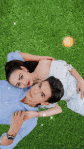 a man and a woman are laying on the grass