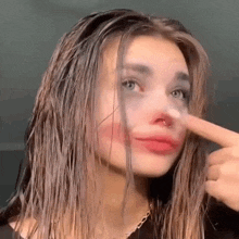 a woman with a nose ring is making a funny face with her finger .