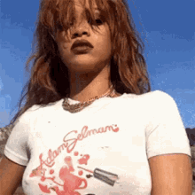 a woman with red hair is wearing a white t-shirt with a picture of a nail polish bottle on it .