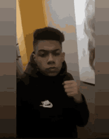 a young man wearing a black nike hoodie is taking a selfie