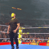 a man in a black shirt and black pants is standing in a wrestling ring with the letter w on it